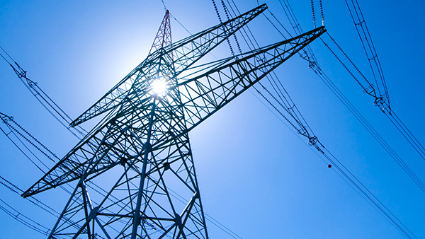 Power lines against the sun in blue sky