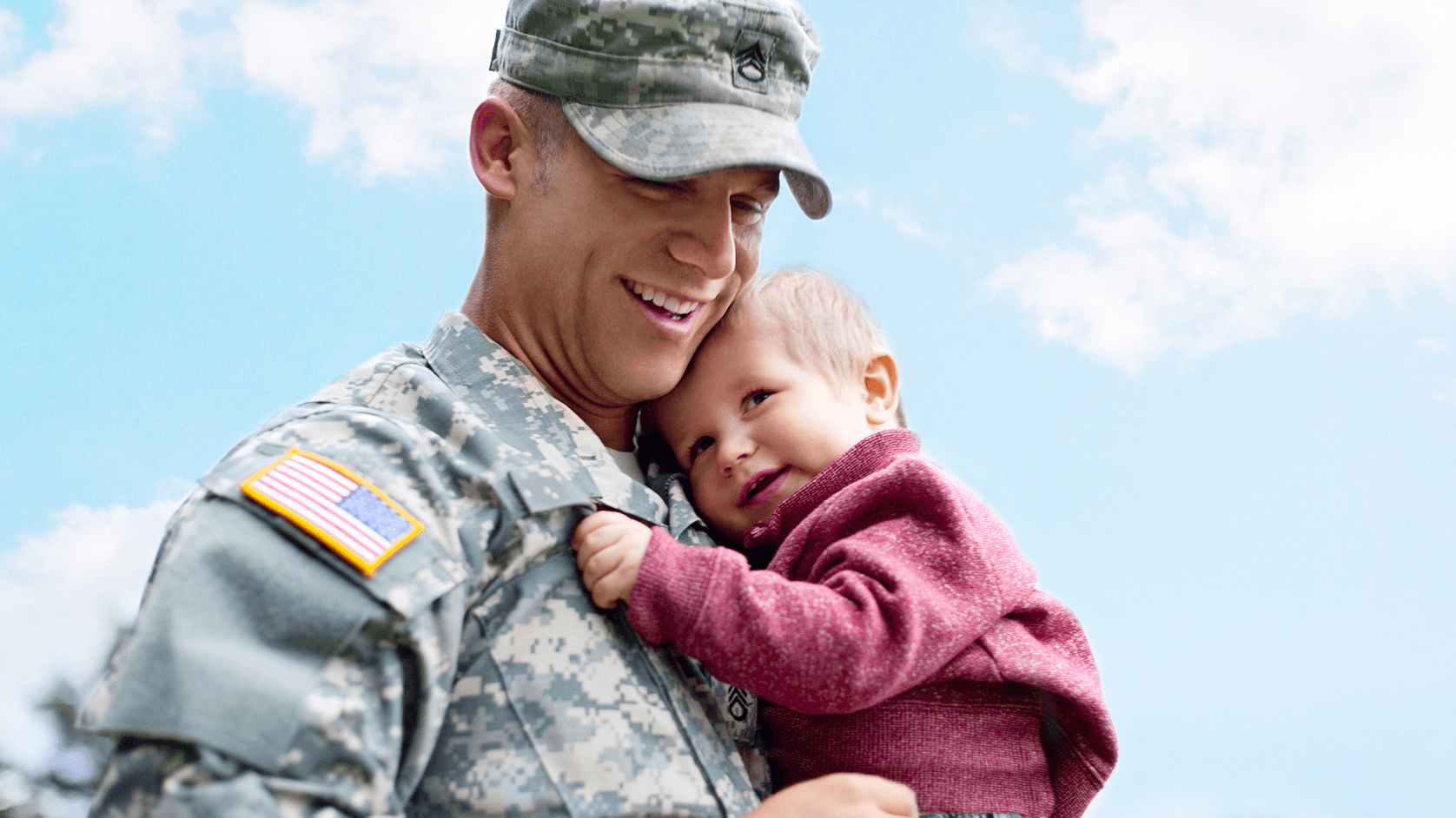 U.S. service member smiling and holding his daughter. 
