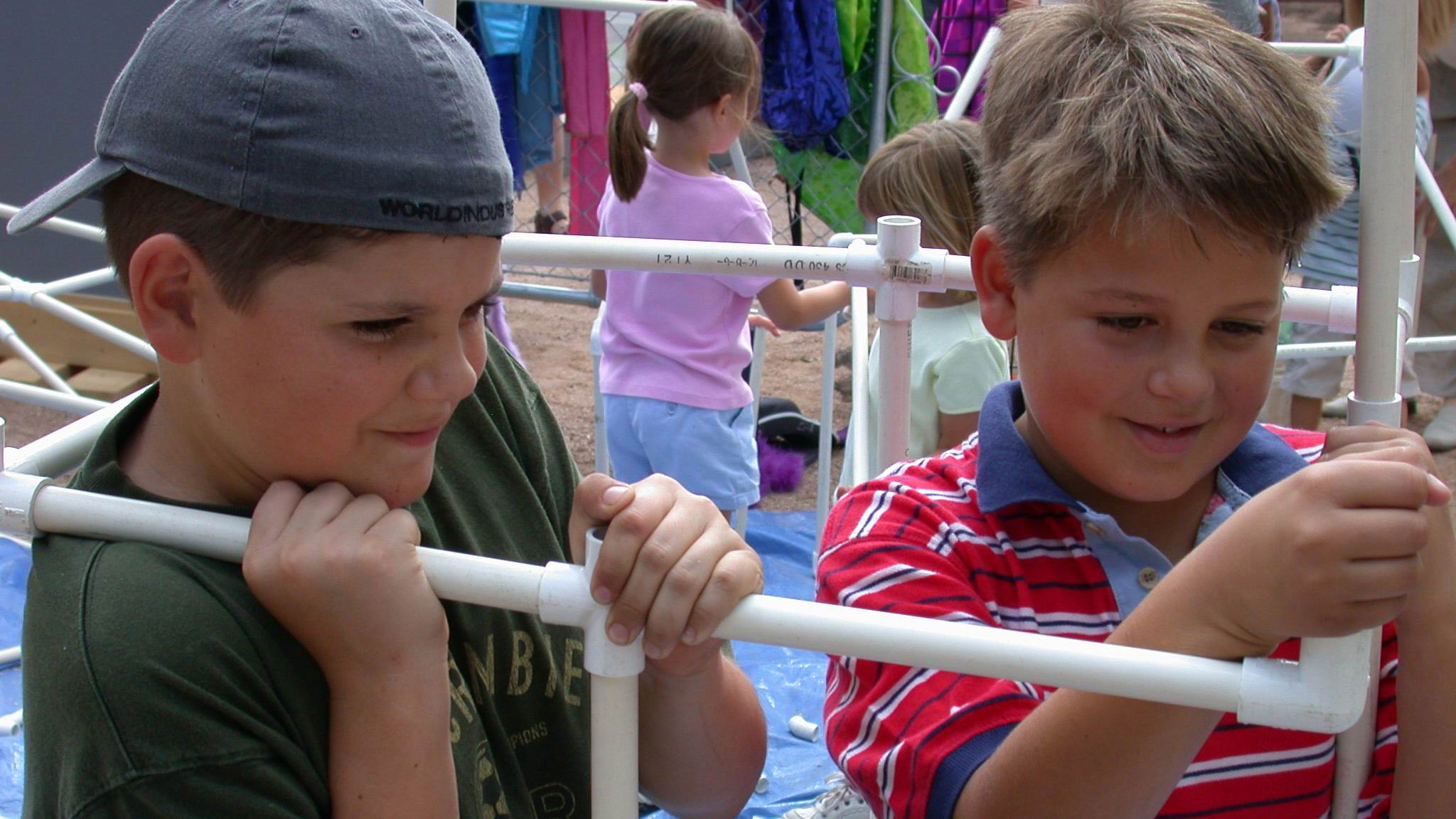 Two young kids working with PVC pipe.