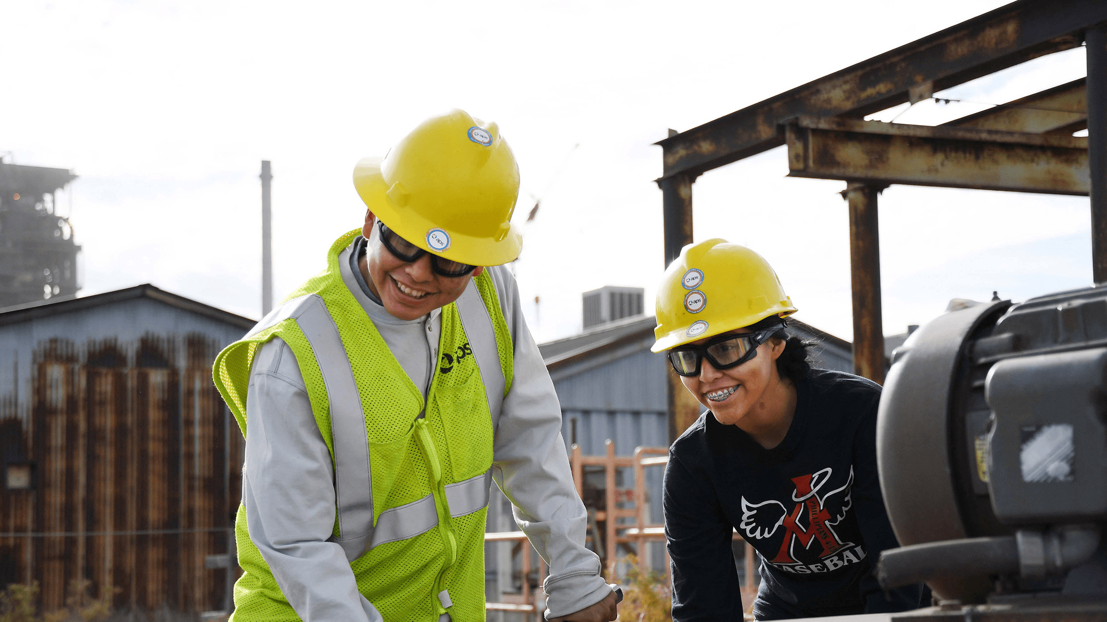 Two APS employees smiling while working at a power plant.