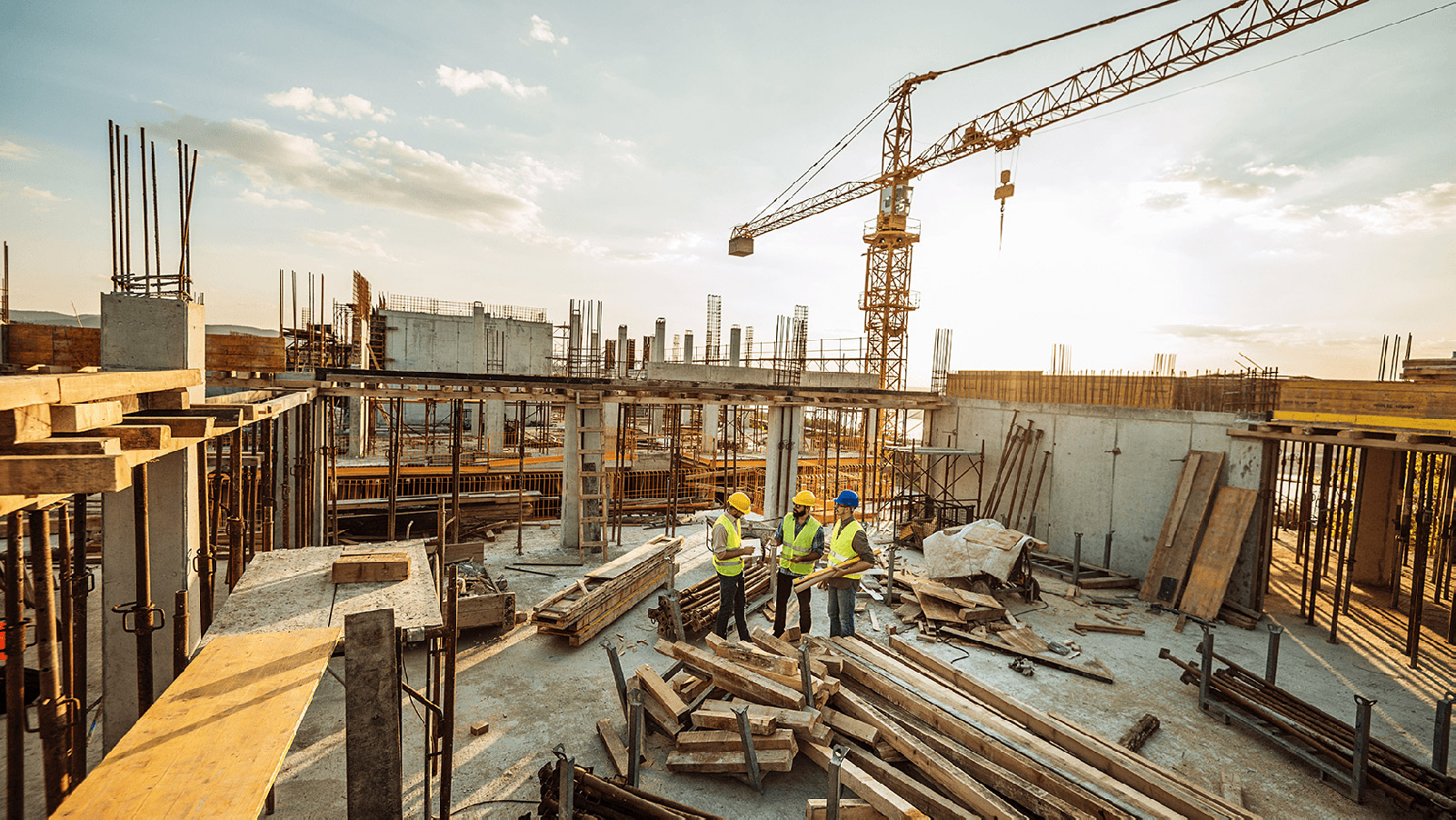 Three construction workers talking within a buidling frame.