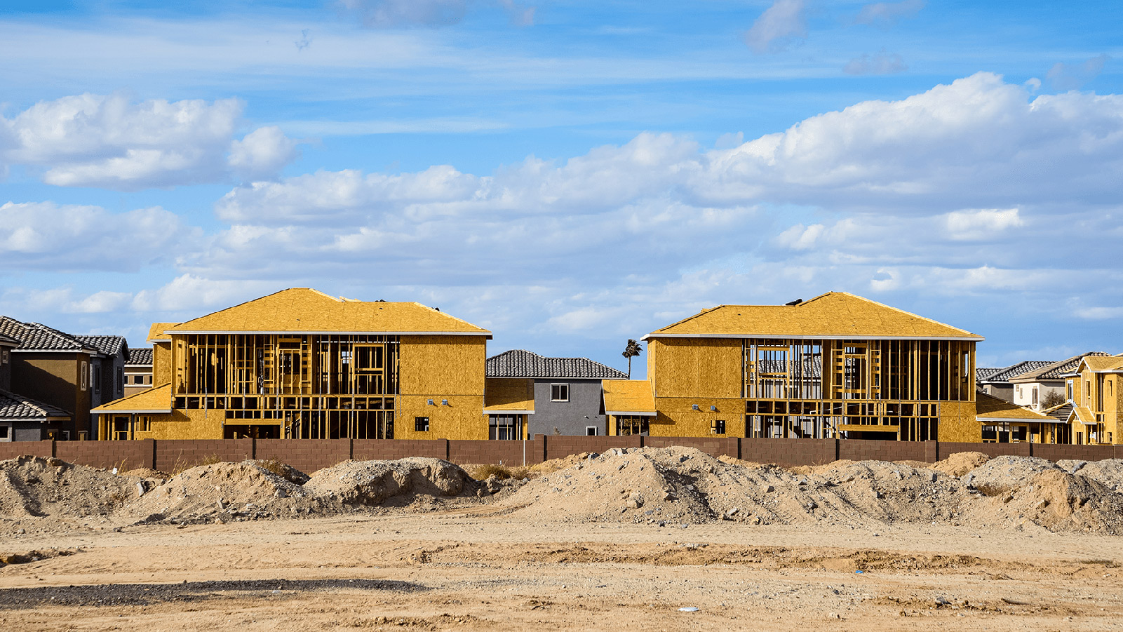 New home construction against a blue sky with clouds.