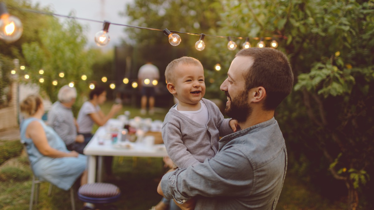 Father holding toddler outside 