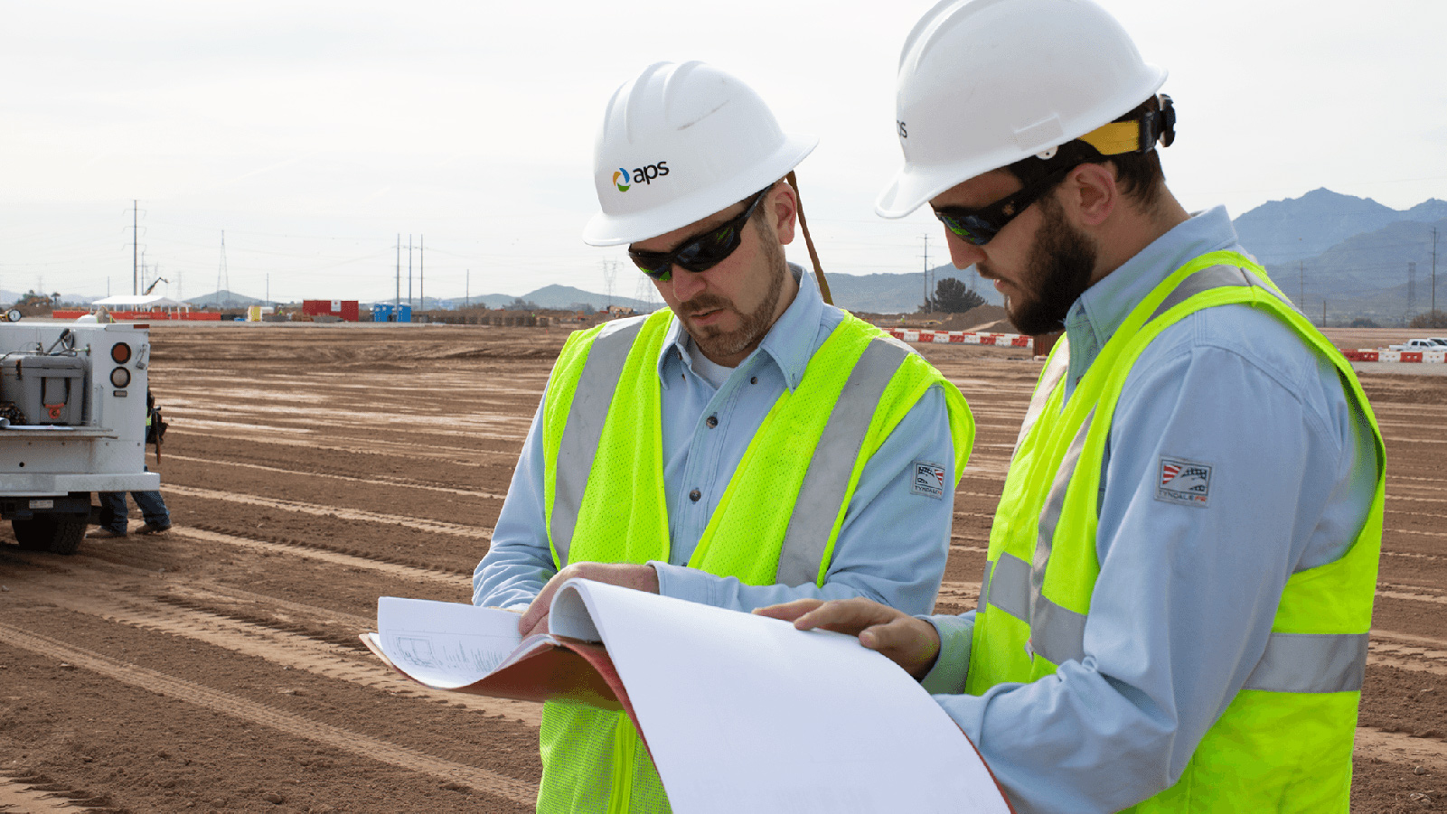 Two APS employees looking at blueprints. 