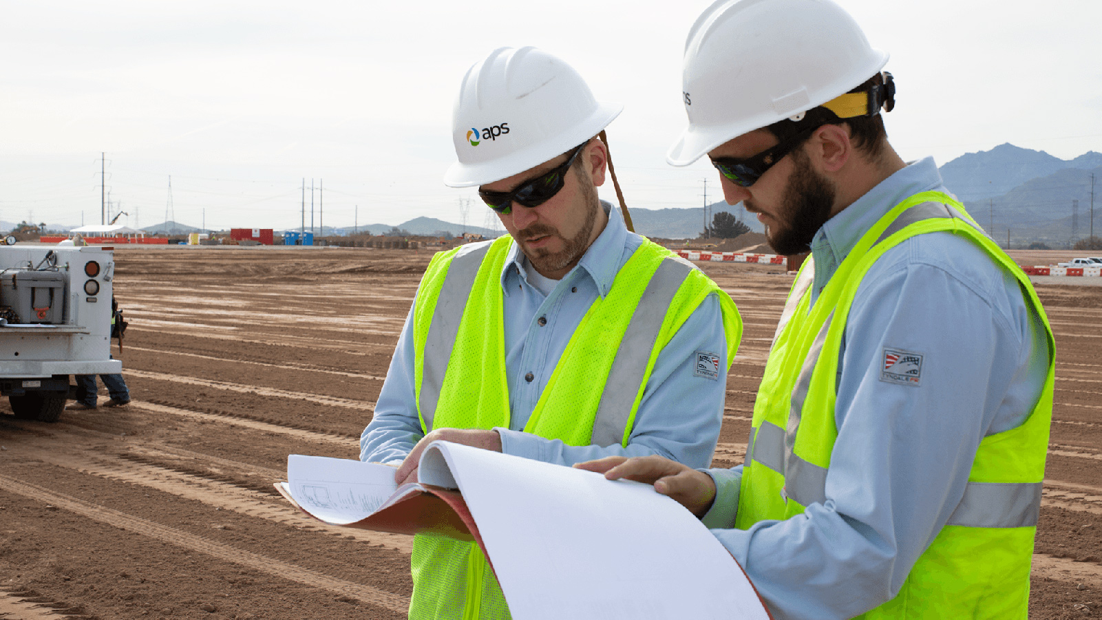 Two APS employees looking at blueprints.