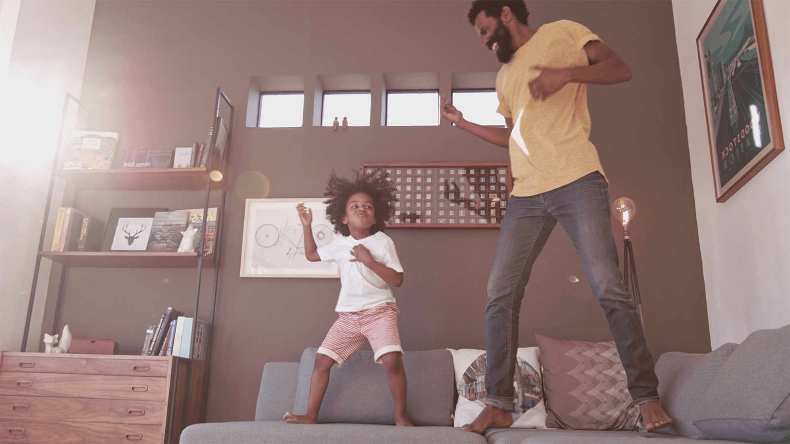 Father and his daughter playing air guitar on the couch.