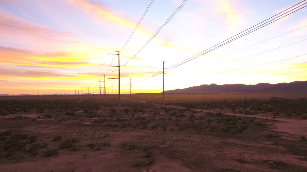 Power lines in the desert against the sunset.