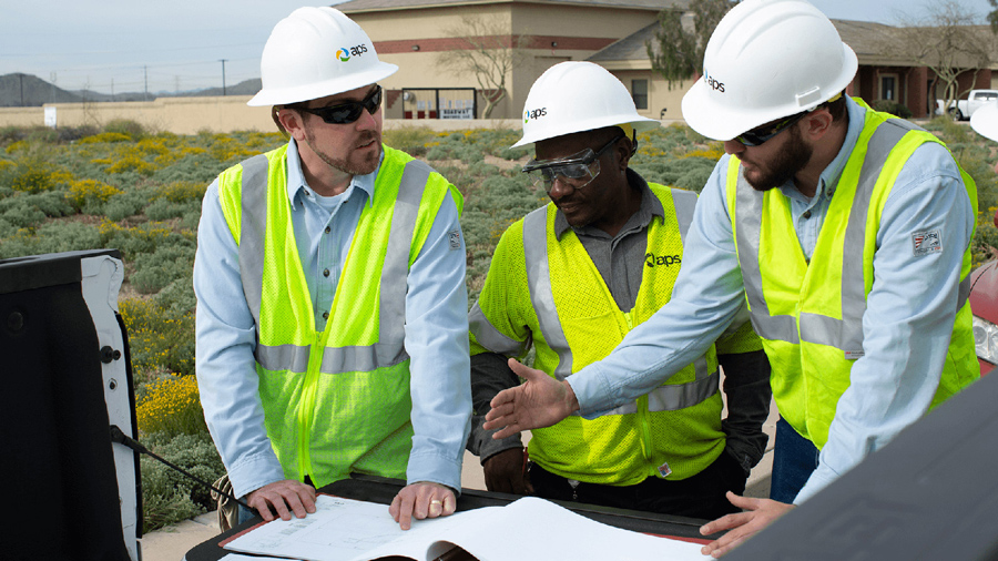 APS employees discussing blueprints on the bed of a truck.