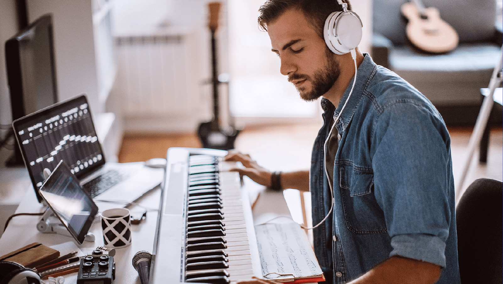 Man with headphones and using a keyboard piano.