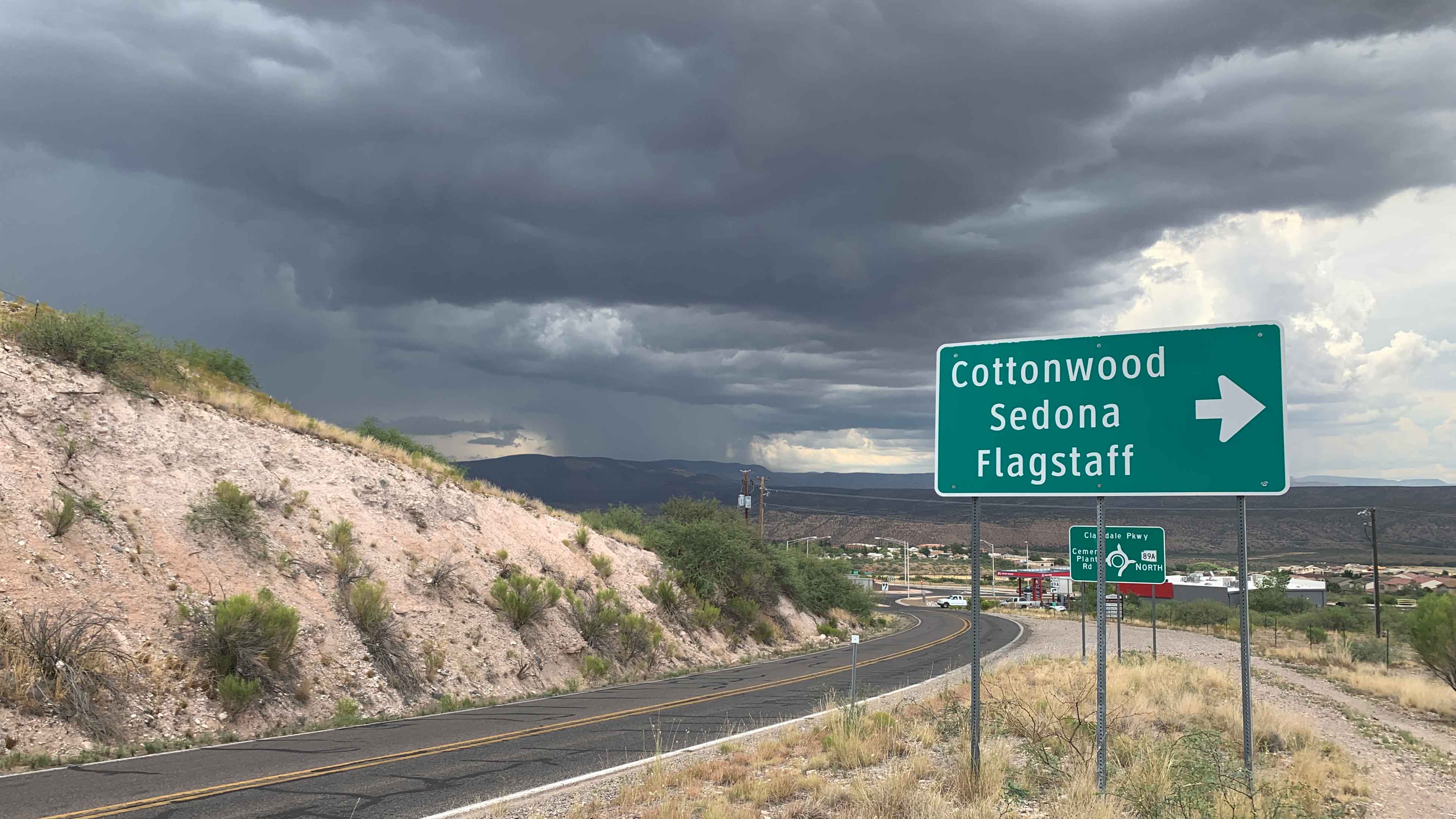 road on the side of a mountain with street sign for Cottonwood, Sedona and Flagstaff 