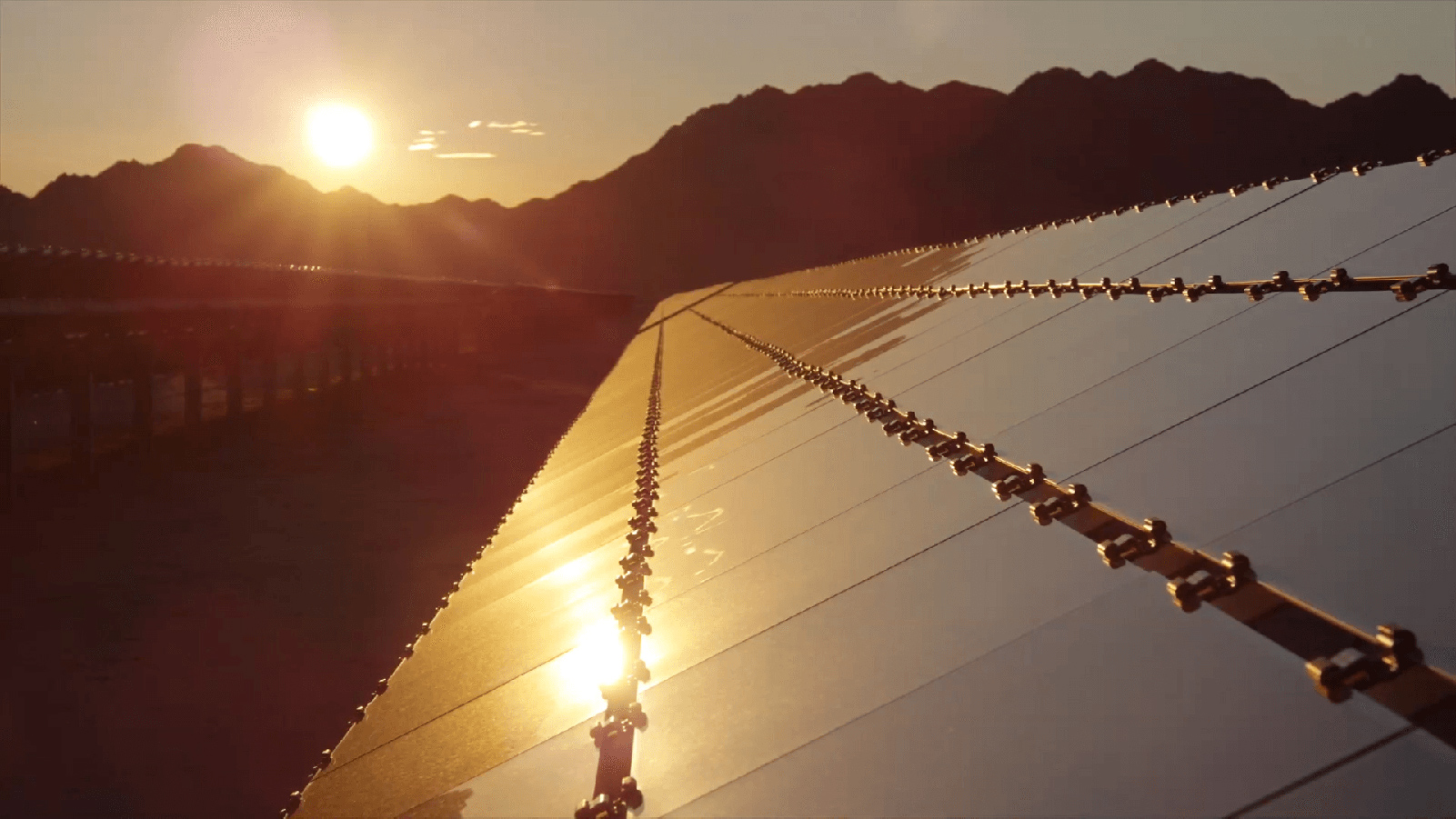Paloma Solar Plant with a mountainscape and setting sun.