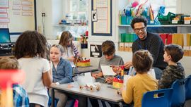 Classroom of students sitting at a table with their teacher.