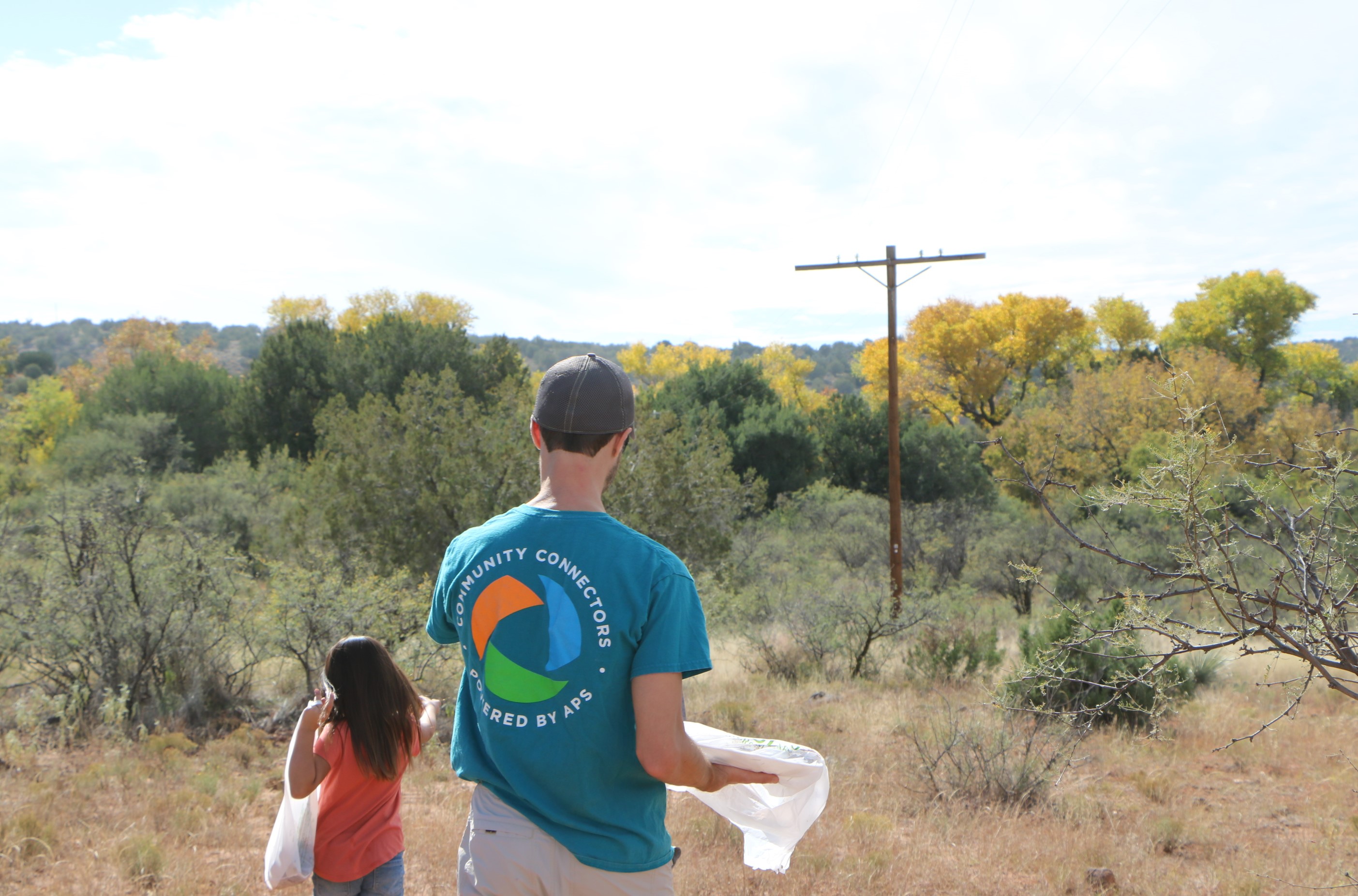 APS employee walking with young girl in desert with bags