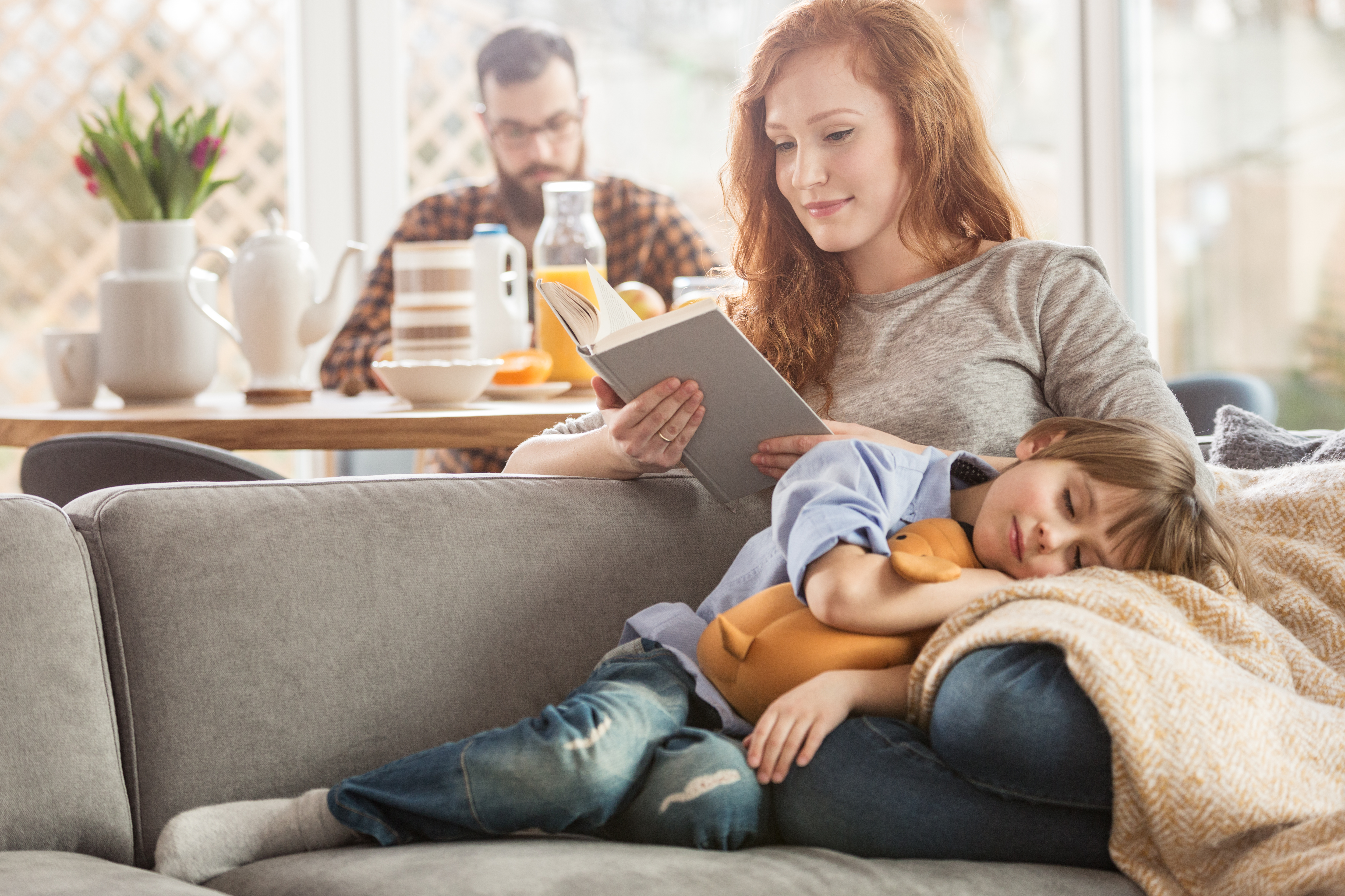 Familia en el sofá con un niño durmiendo en el regazo de la madre.