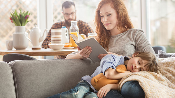 Family on the couch with a child sleeping on the mothers lap