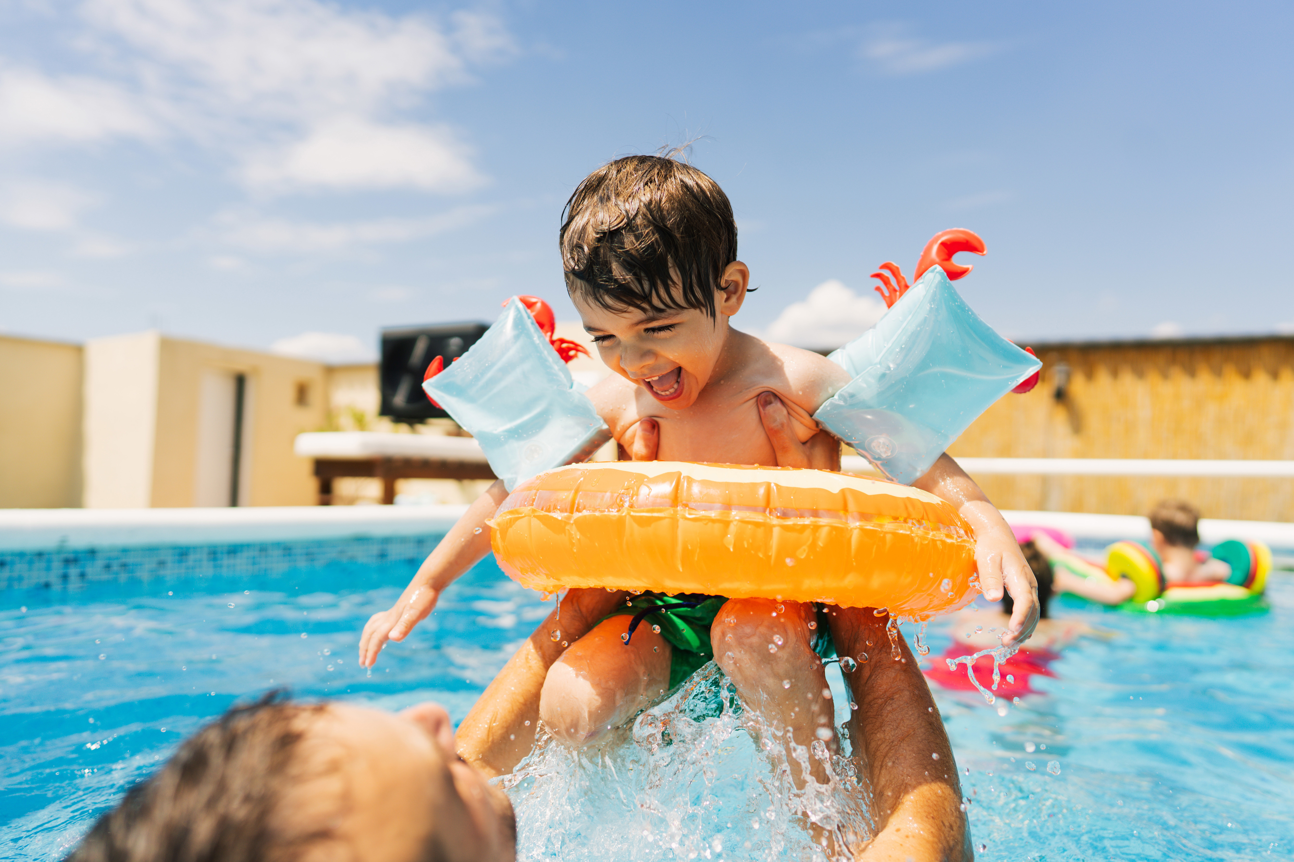 Child and parent playing in pool