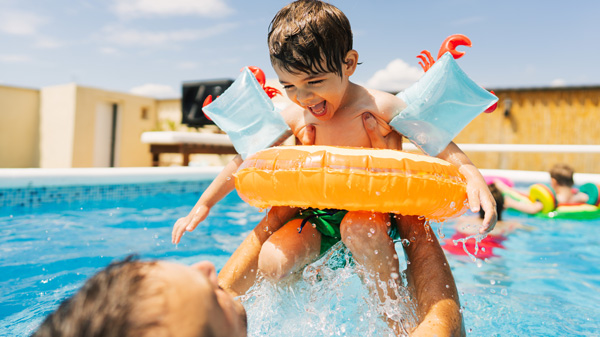 Child and parent playing in pool 
