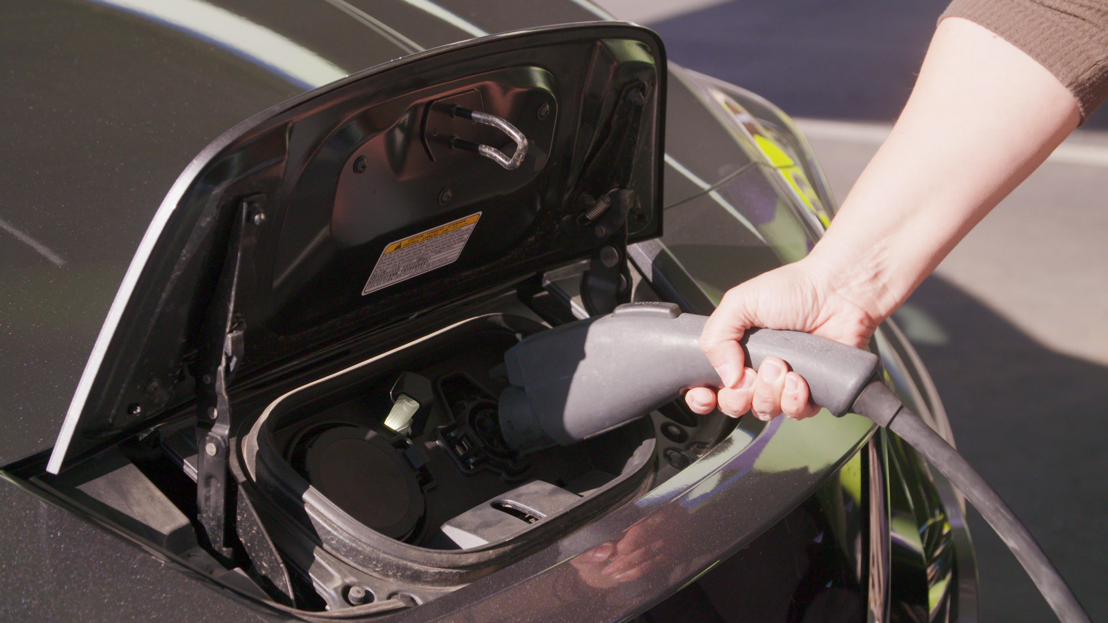Close up view of someone plugging in an electric vehicle to a charging station