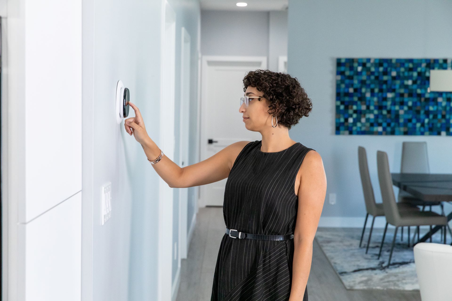 Woman in living room adjusting a thermostate