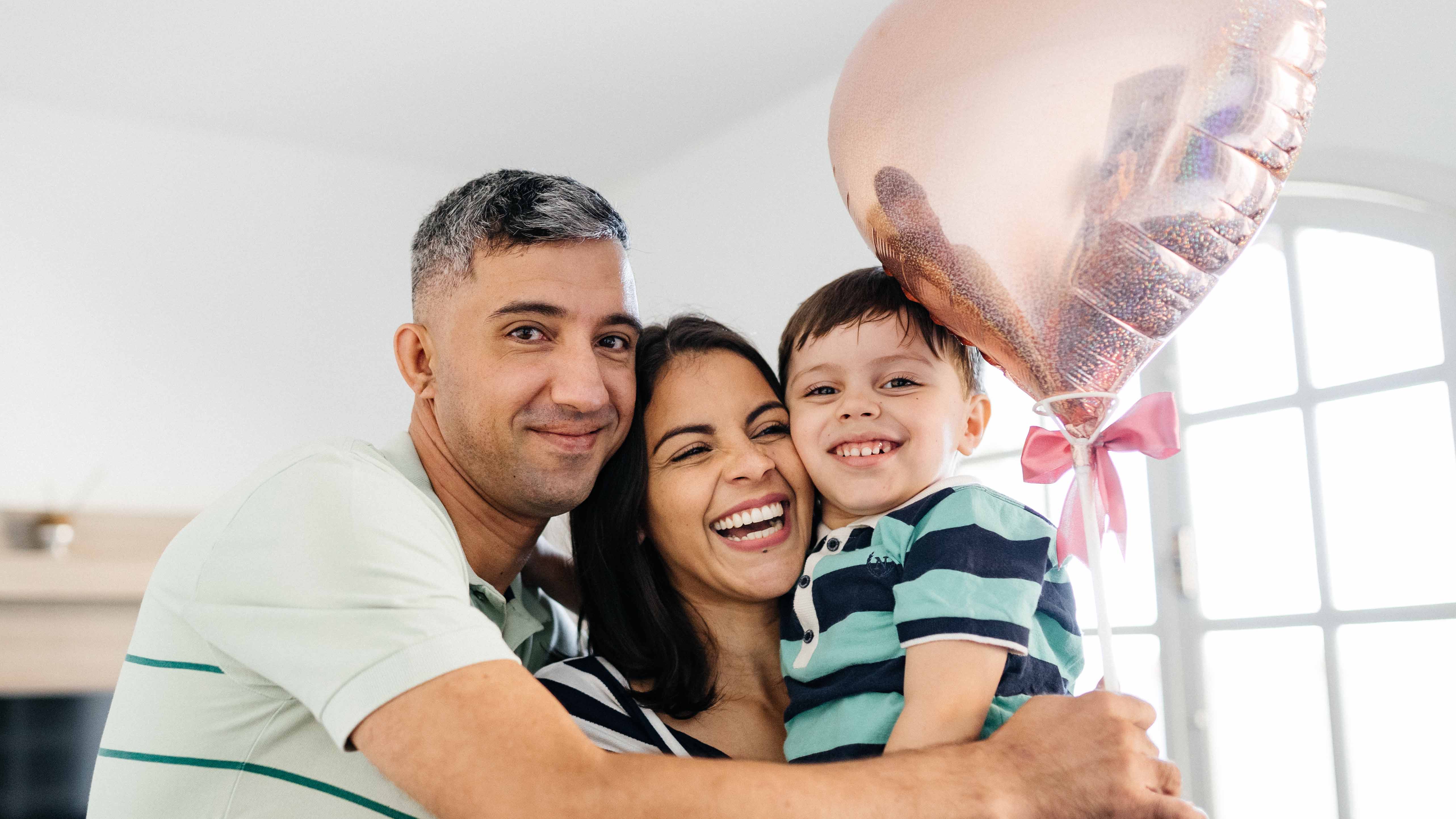 Young family hugging with a hear balloon