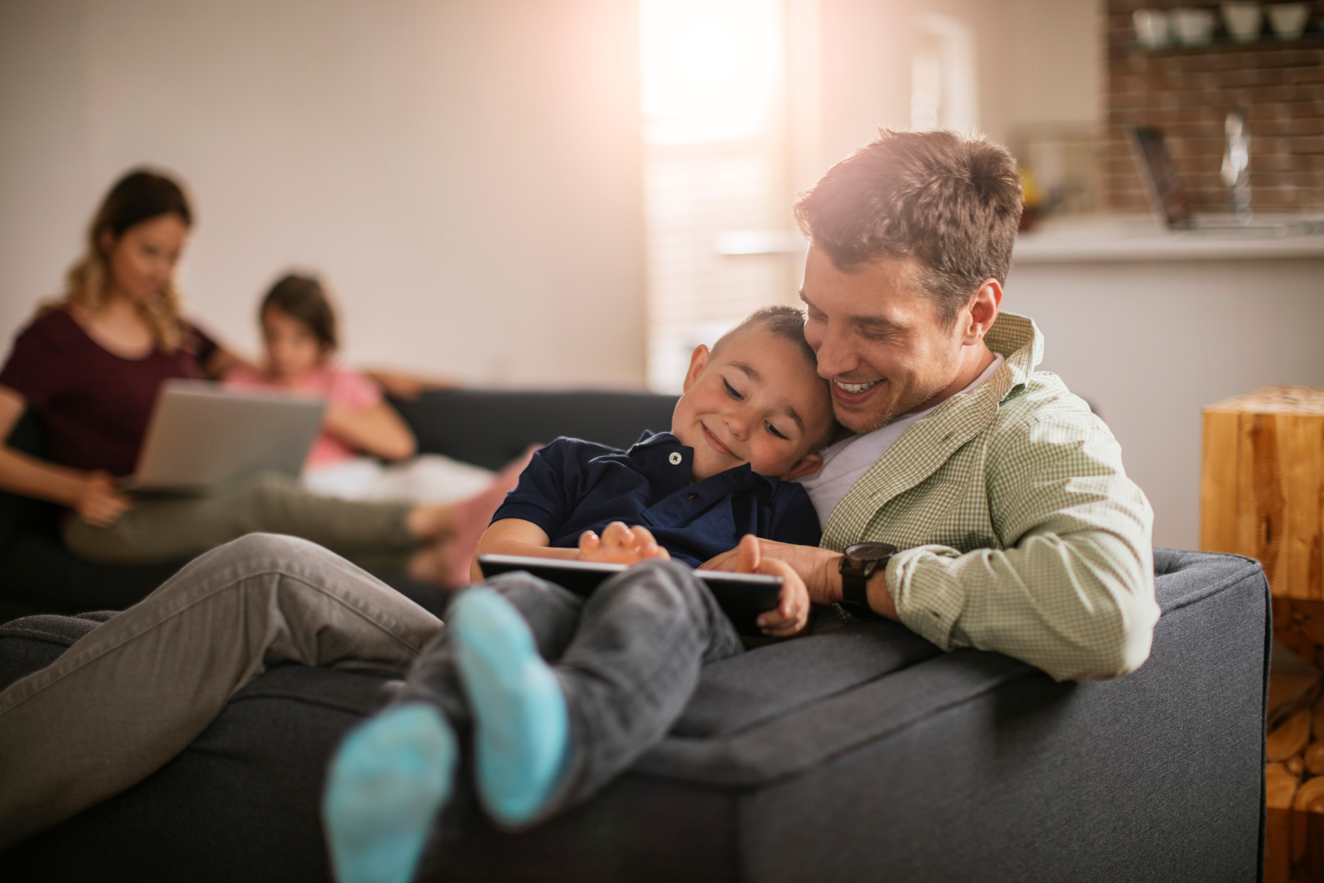 Family in the living room, father and son on a tablet