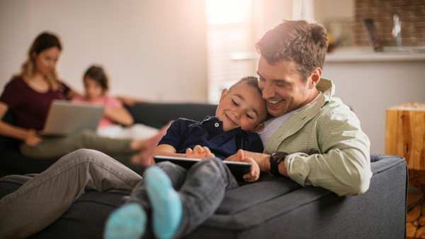 Family in the living room, father and son on a tablet