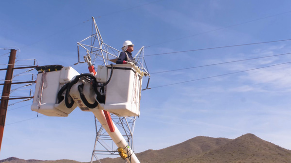 APS Employee inspects lines from bucket truck