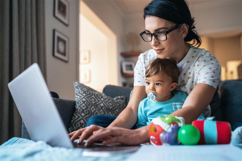 Mujer usando una computadora portátil con un bebé en el regazo
