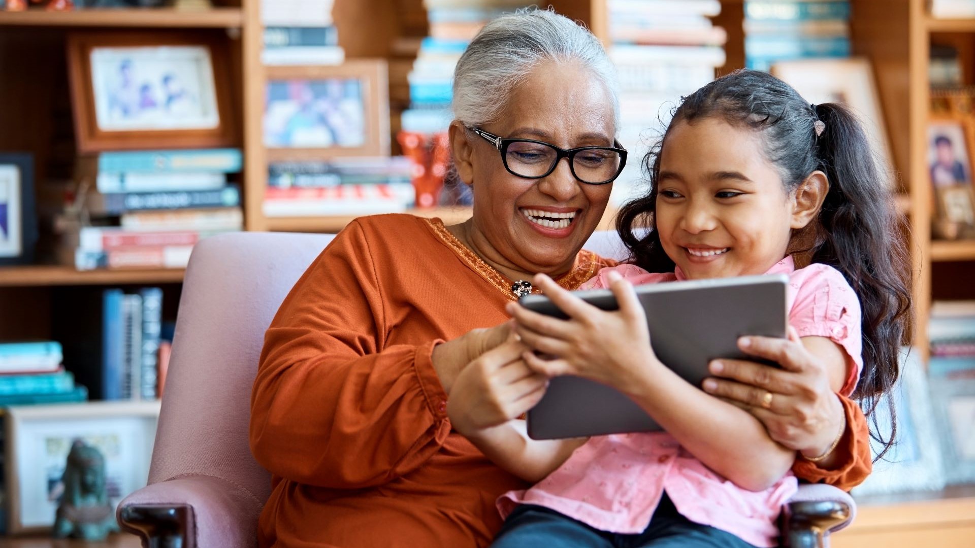 Grandmother looking at a tablet with young girl on her lap