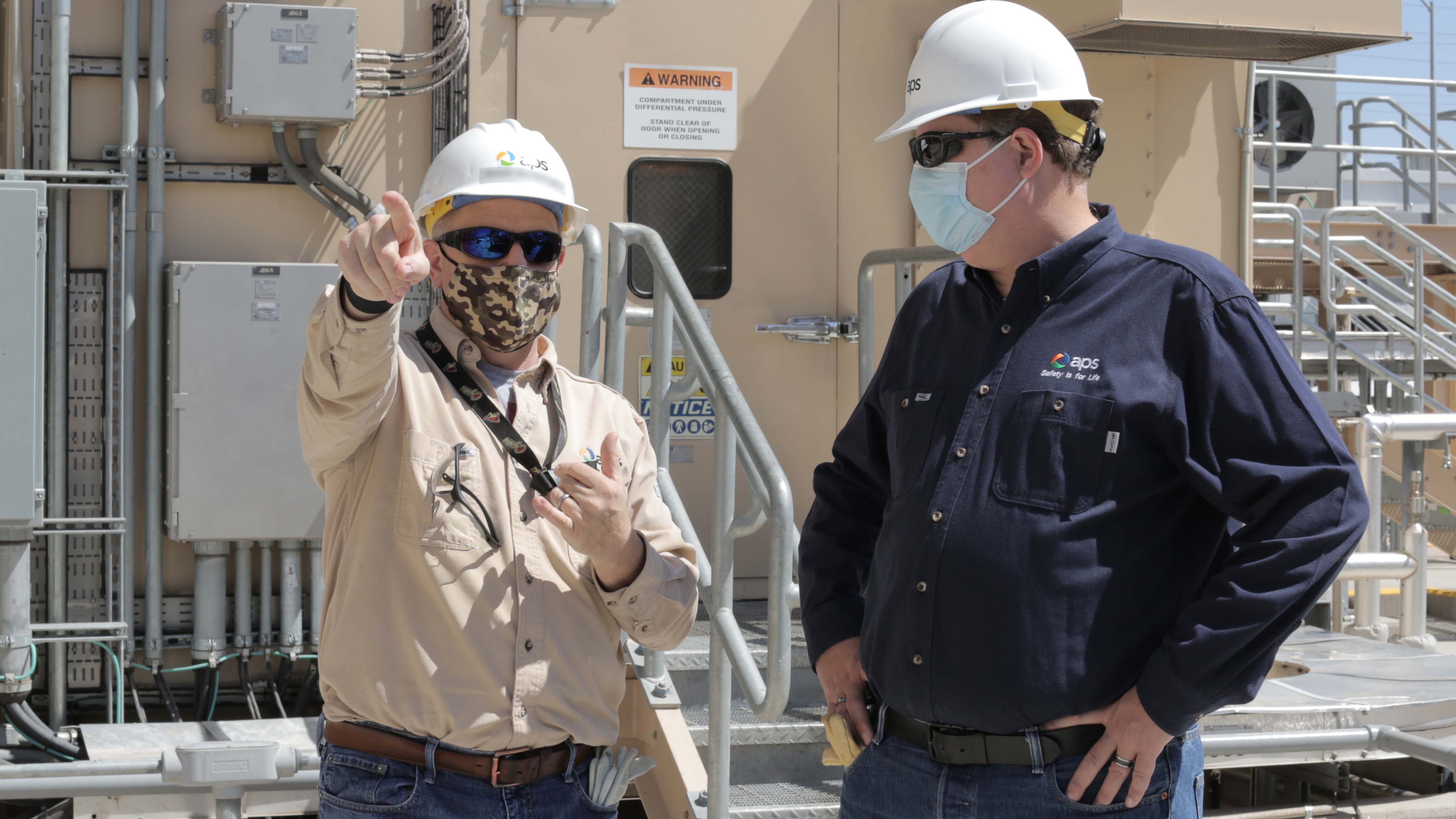 Jeff Guldner, APS CEO speaking with another APS employee outside wearing hard hats