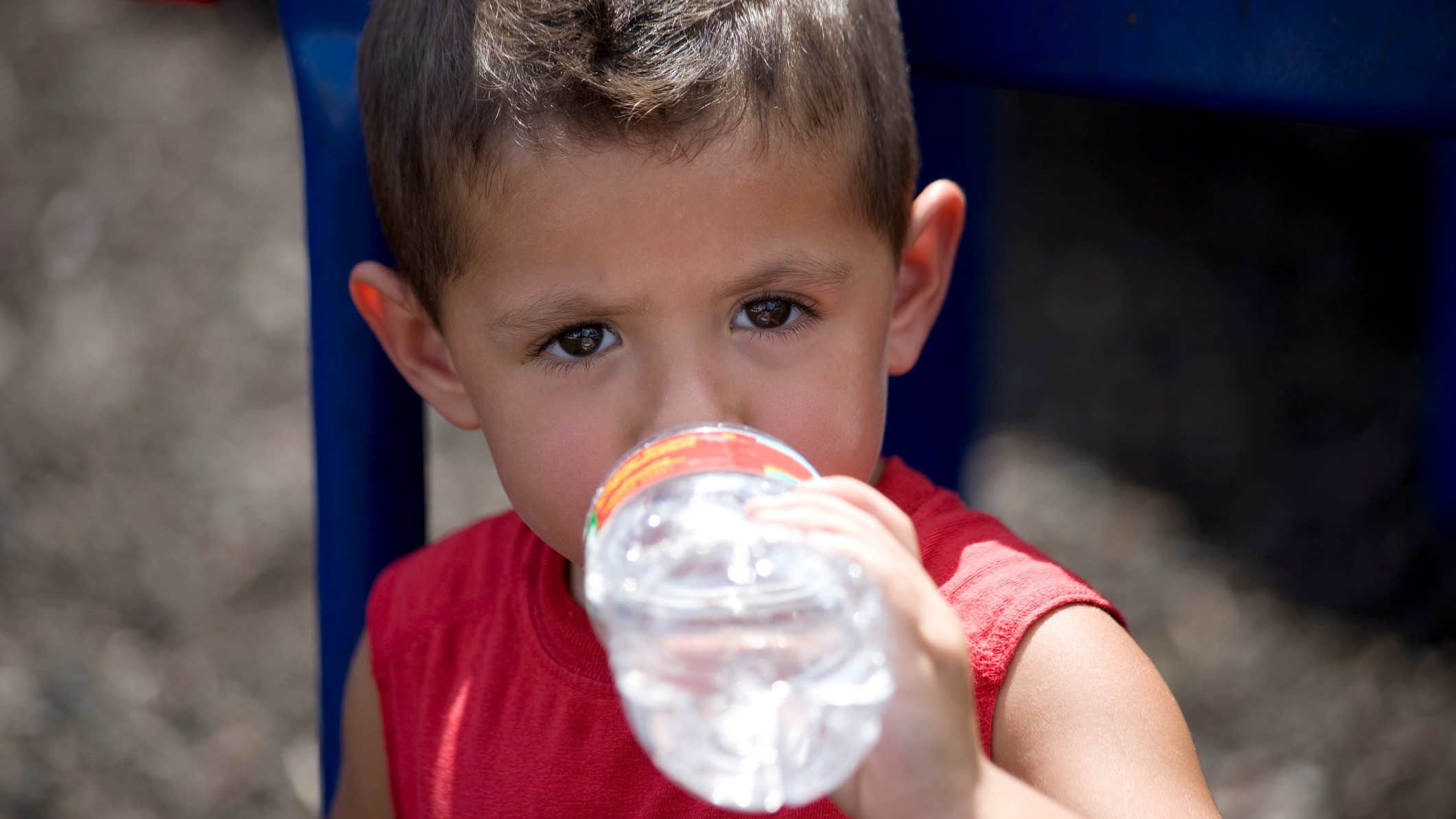 young boy drinking from a bottle of water