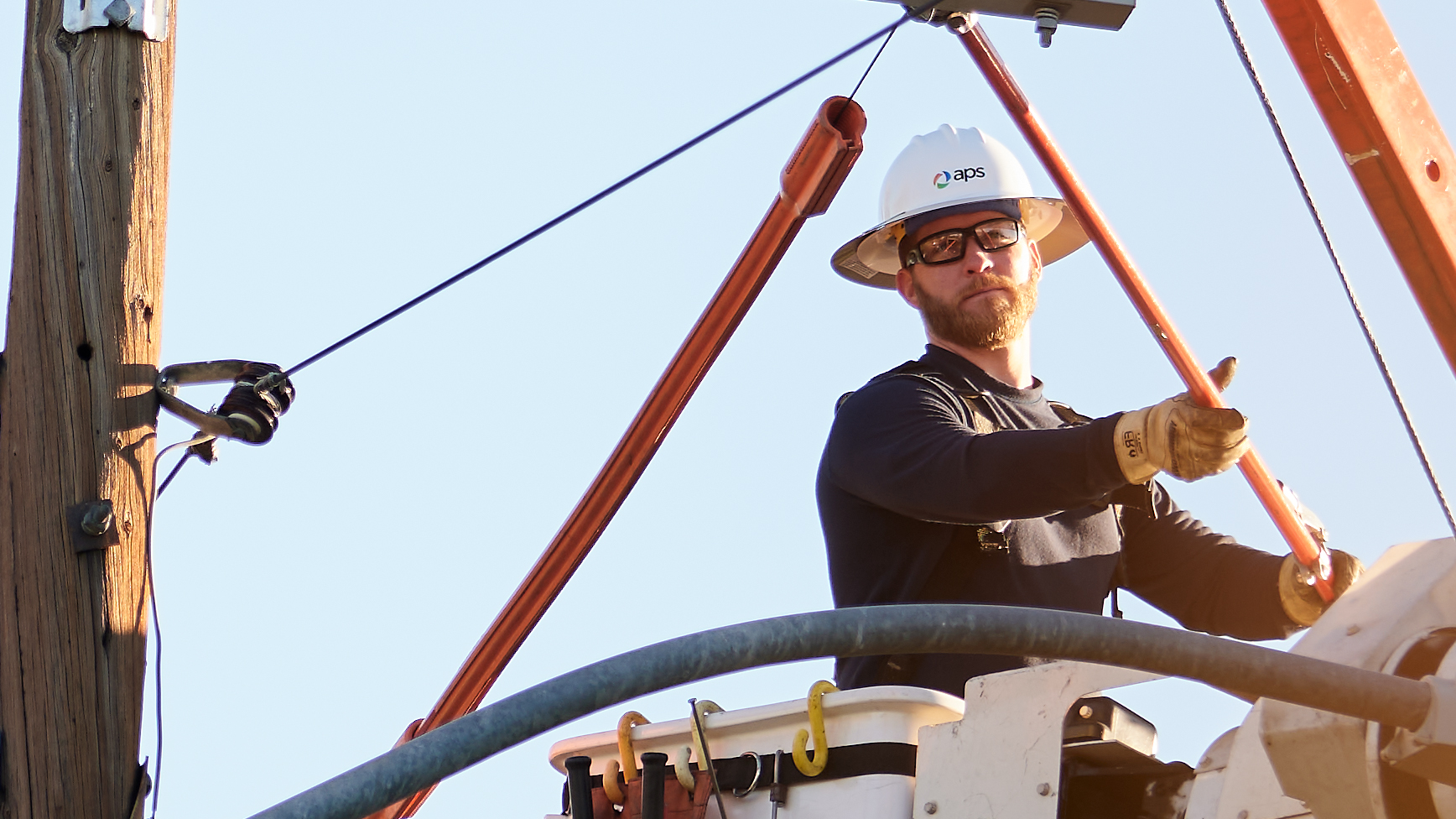 Primer plano de un trabajador de línea en un camión con plataforma trabajando en un poste de energía eléctrica.