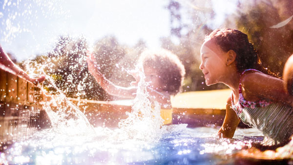 Kids swimmng in a sunny pool