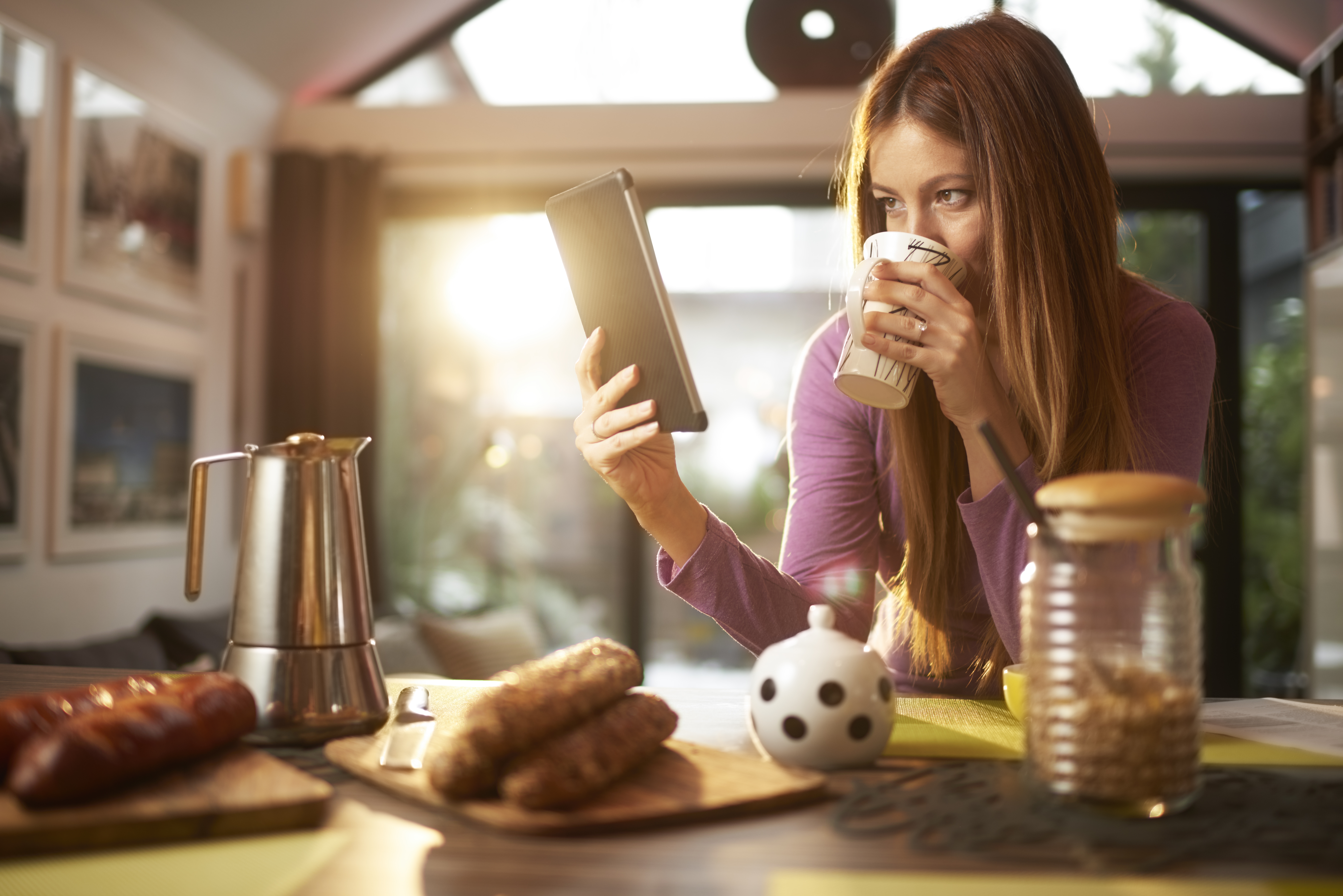 Lady drinking coffee looking at tablet