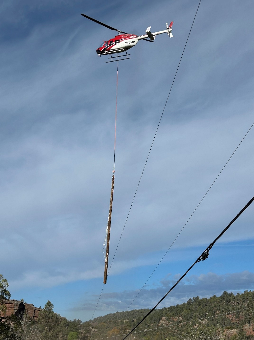 Helicopter carrying a power pole to it's installation point