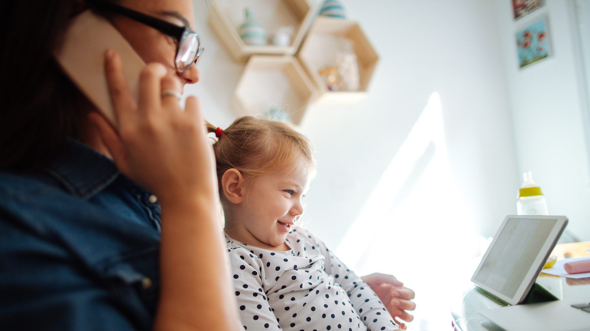 Little girl and mom looking at tablet while on the phone.