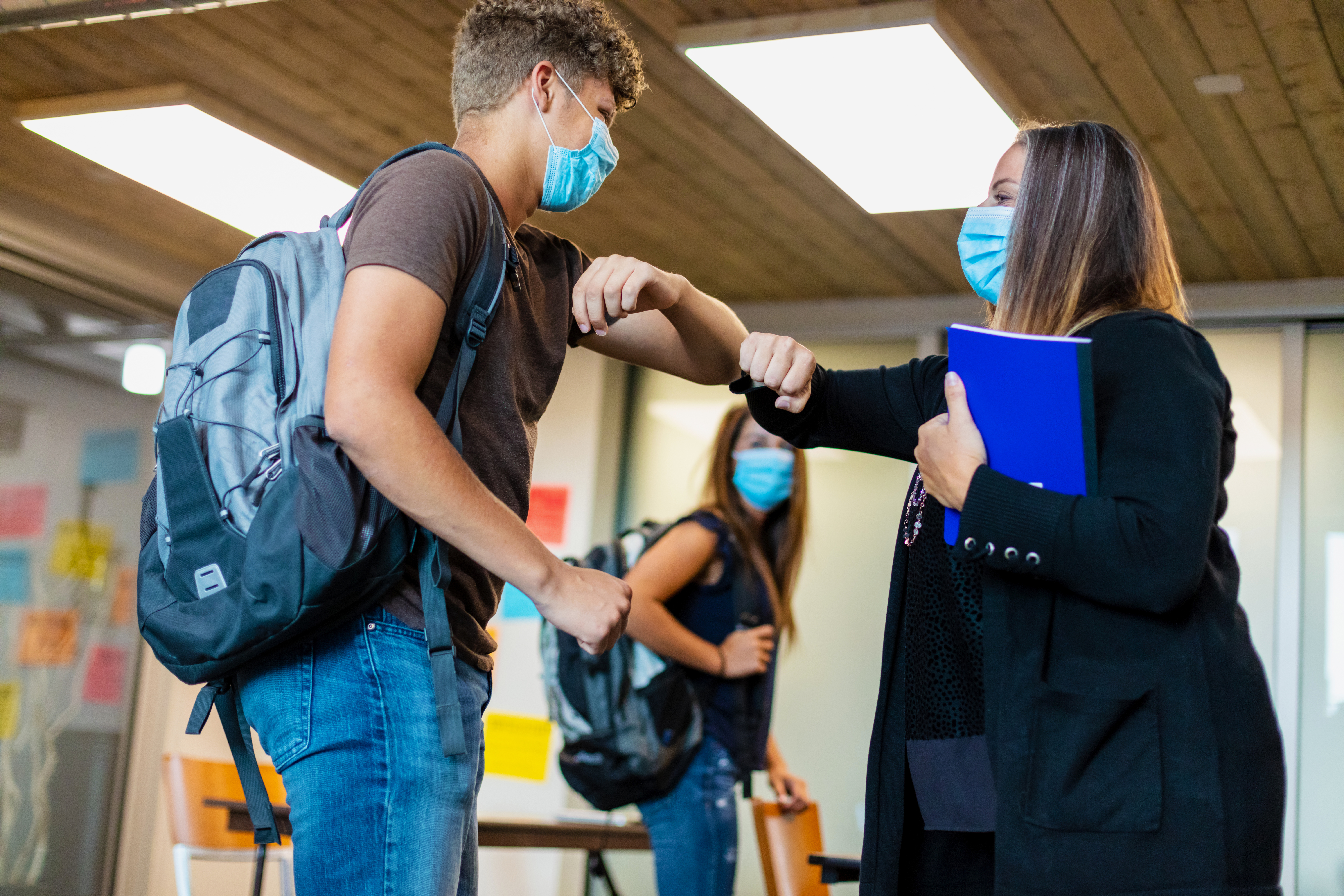 Students wearing masks greeting a school official