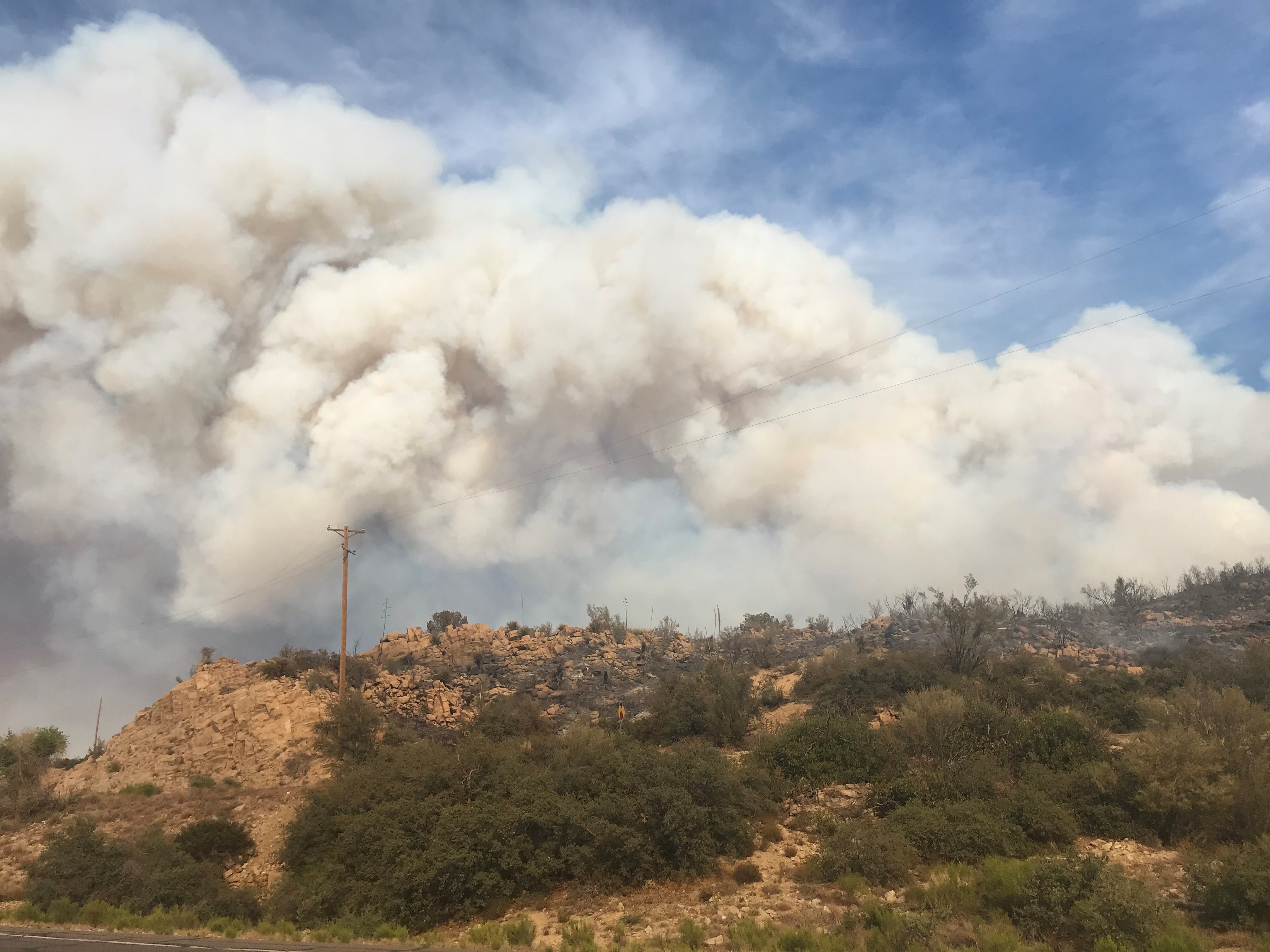 Large clouds of smoke on the top of a desert mountain