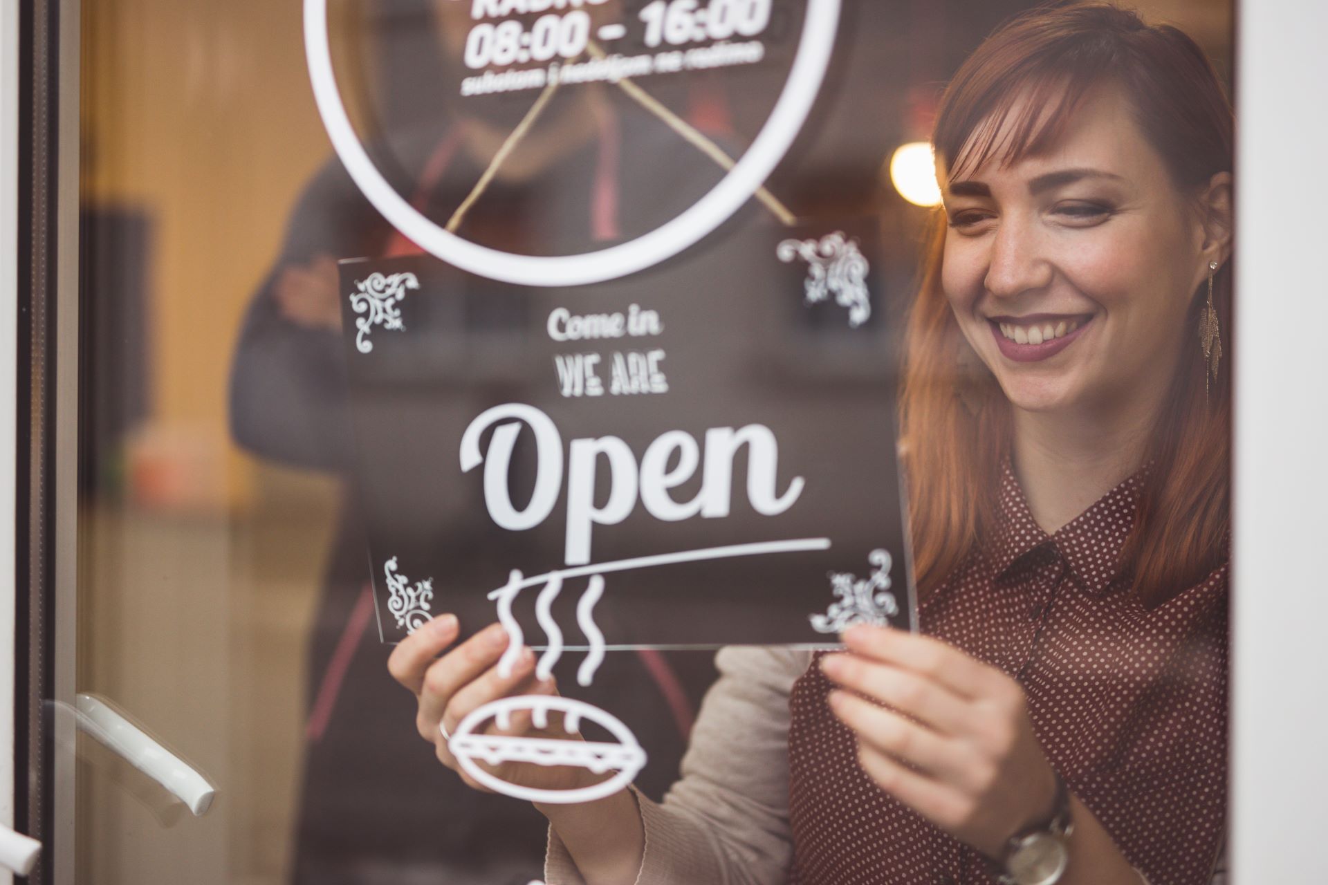 Woman putting the open sign up at business 