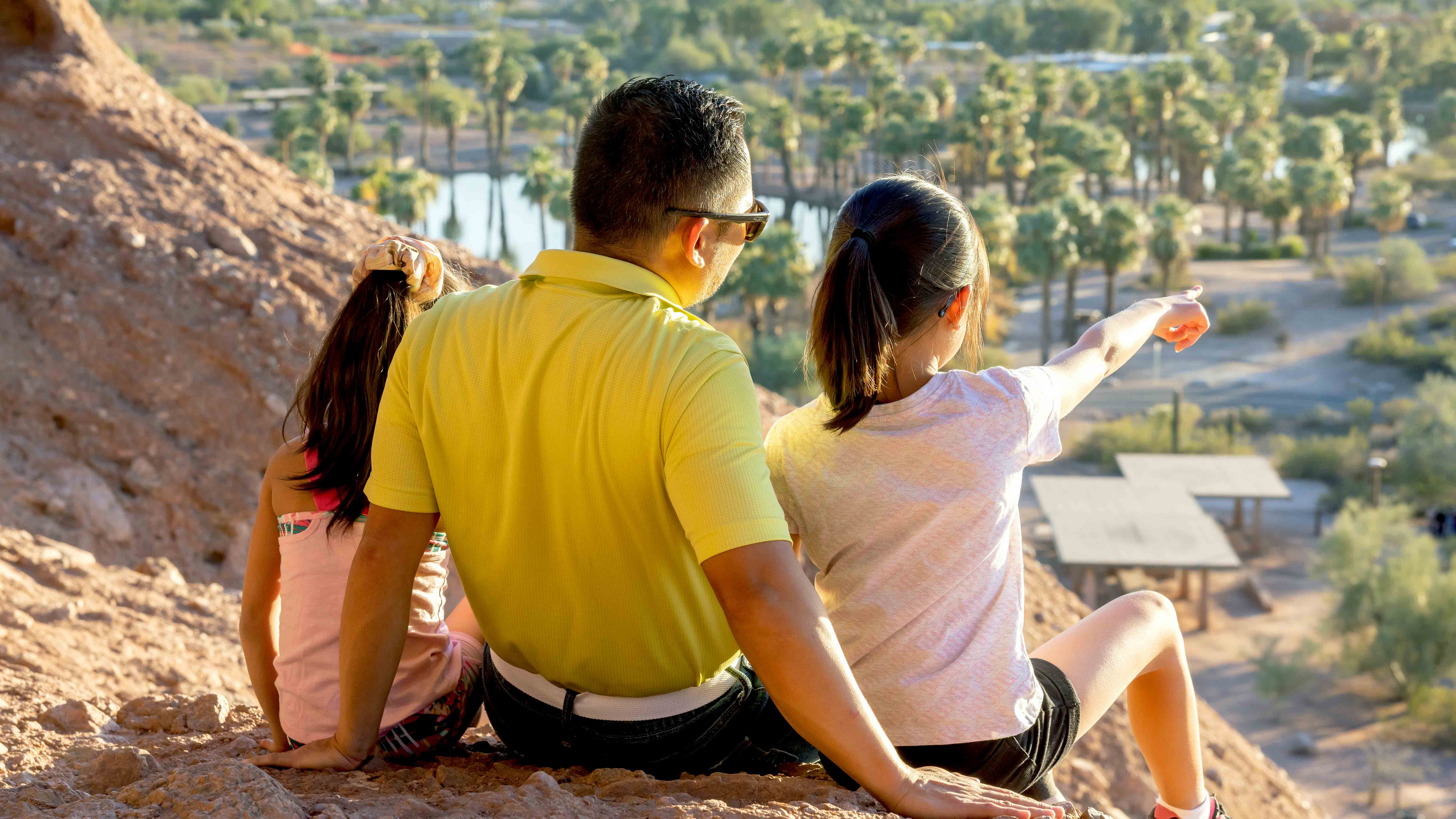A young family sitting on a mountain top looking down at the city
