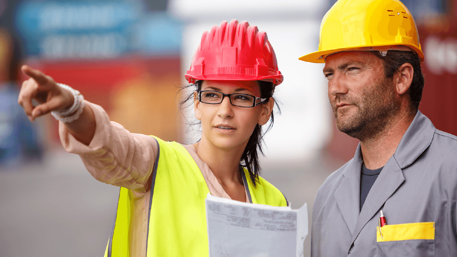 Dos trabajadores de la construcción señalando y mirando un sitio. 