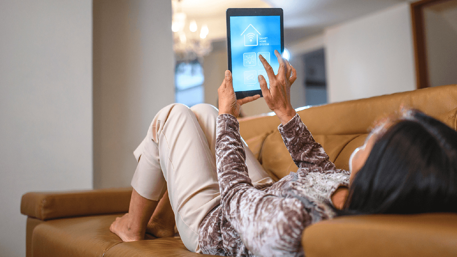 Woman laying on leather couch using tablet.