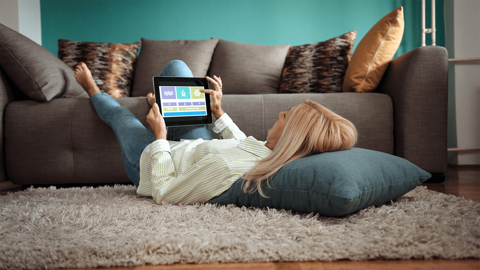 Woman relaxing on her living room floor and using her tablet.