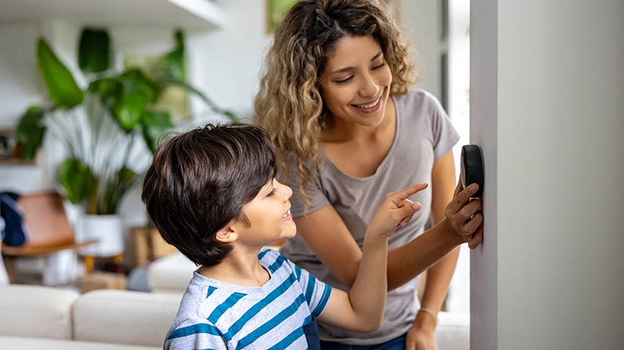 Mother and son adjusting a smart thermostat