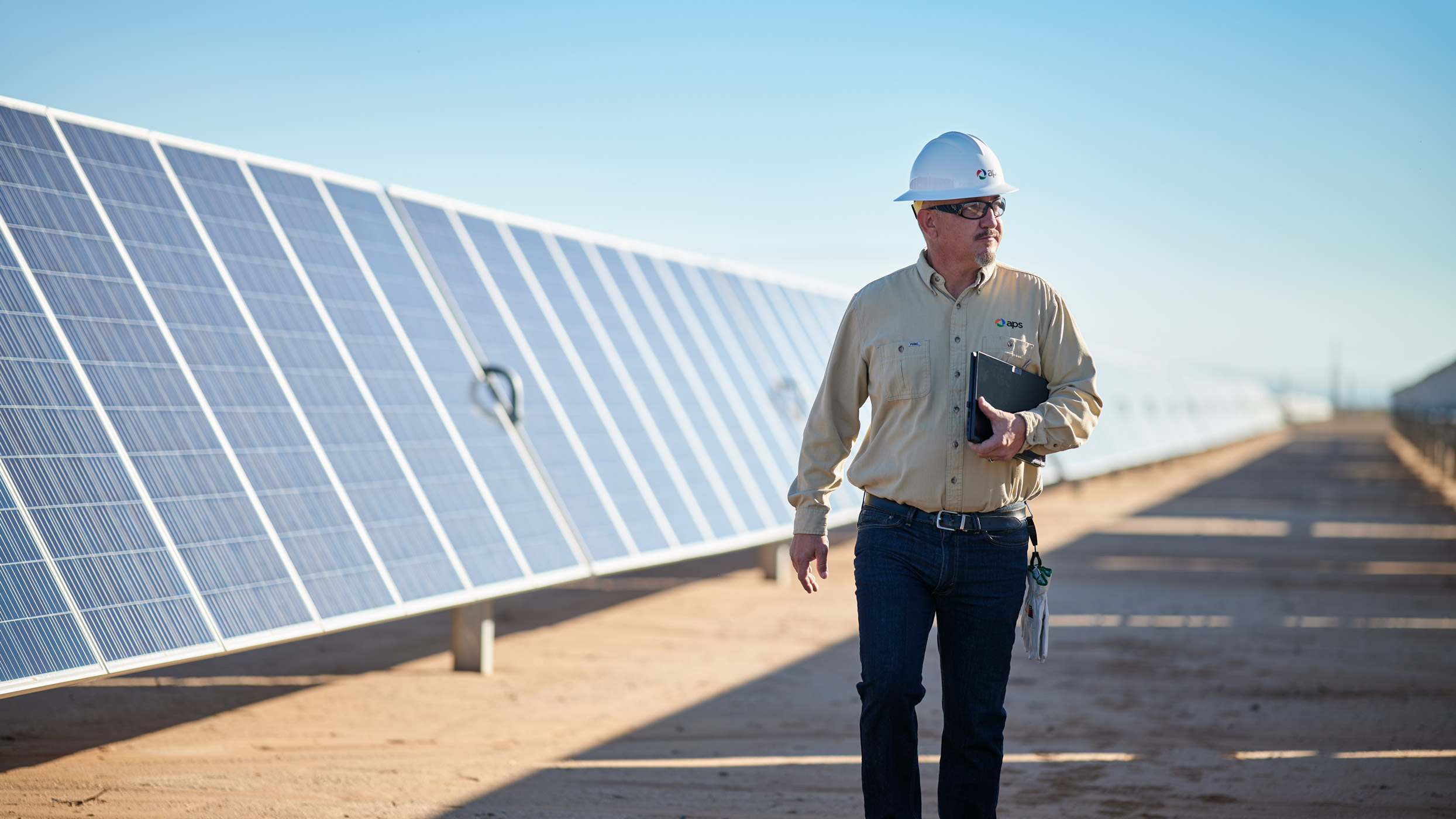 APS plant worker walking through a solar panel field 