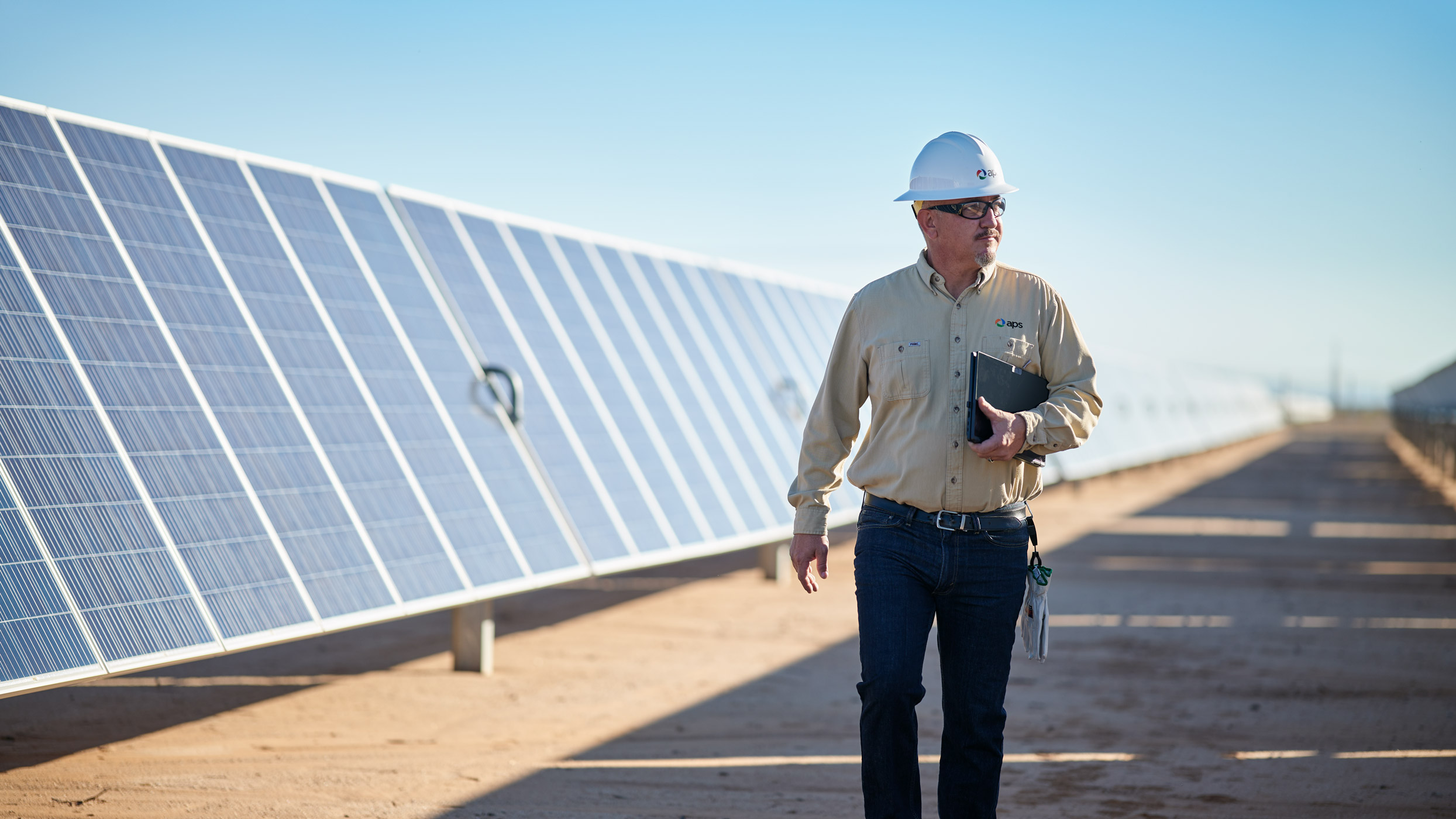 APS plant worker walking through a solar panel field
