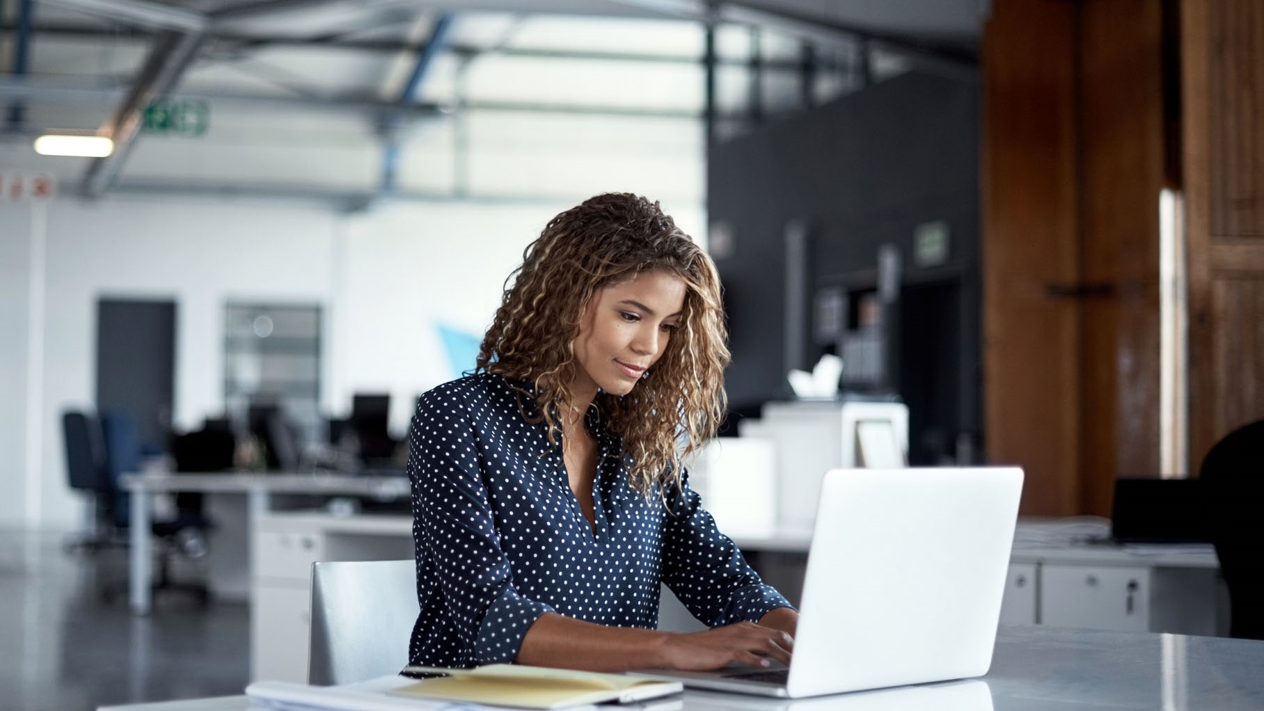 Woman in an office typing on a laptop