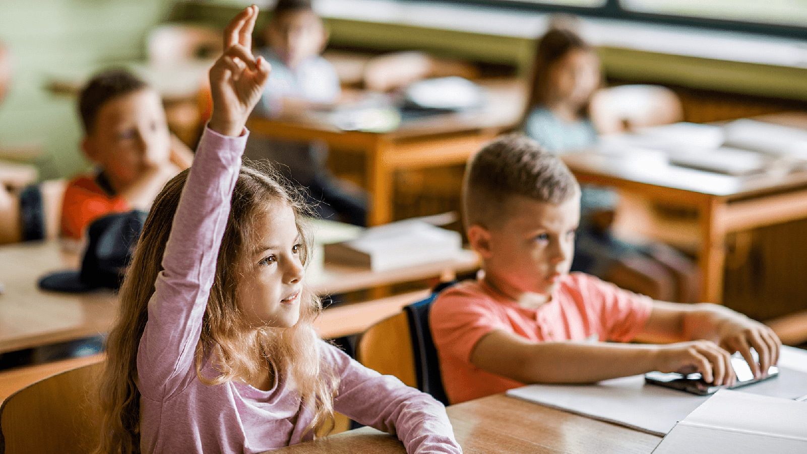 Little girl raising her hand in class.