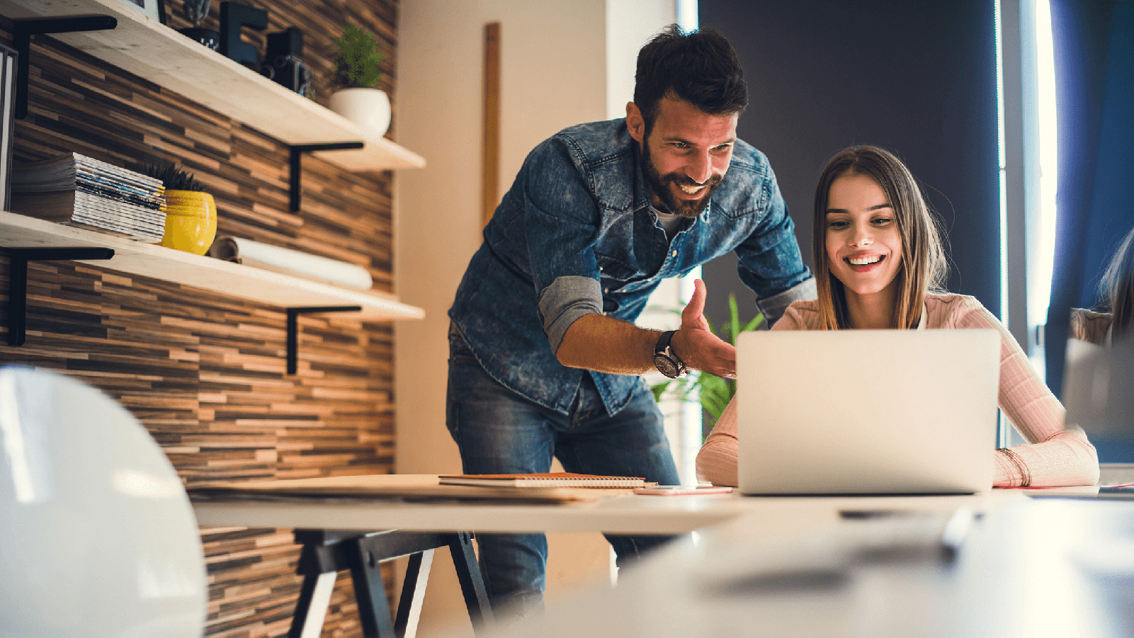 Two people smiling and looking at a laptop.