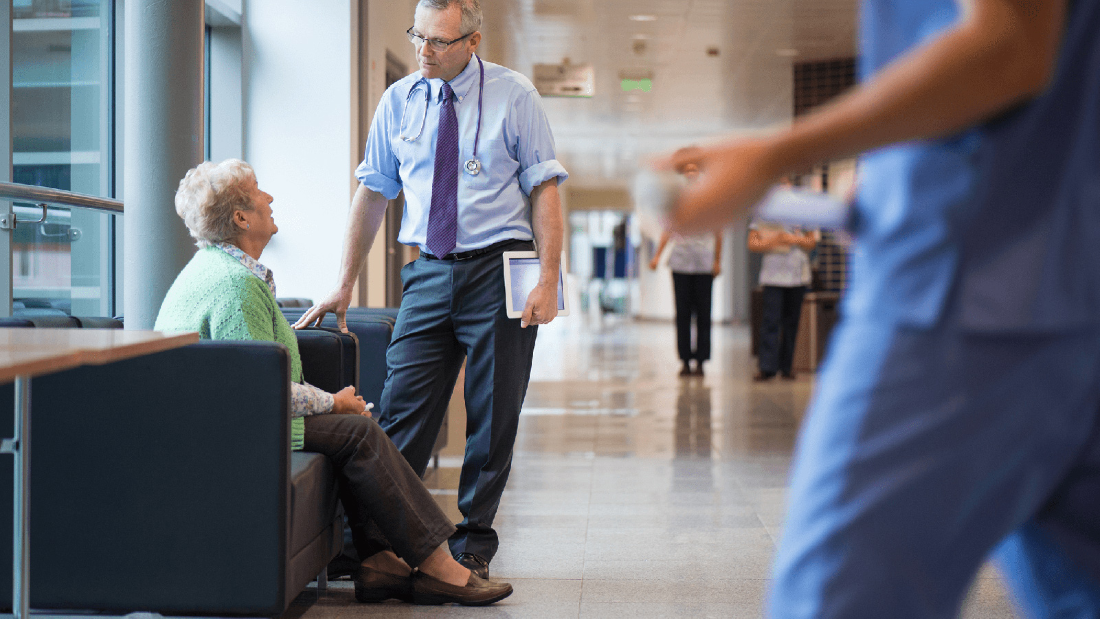 Medical professional speaking with a woman in the lobby of a medical building.